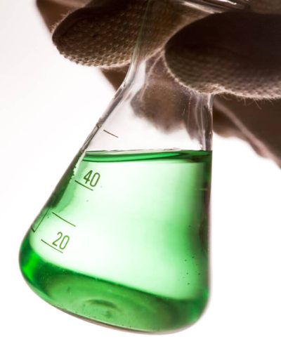 conical flask with green liquid hand laboratory glass scaled